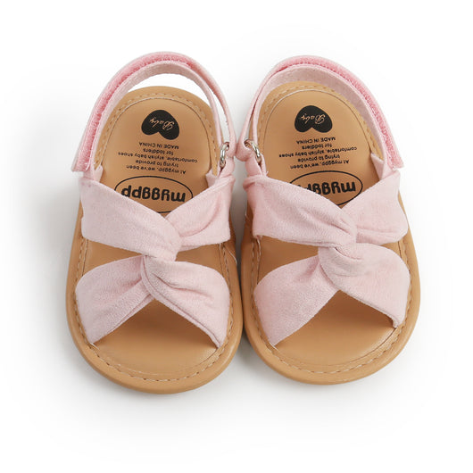 Black baby sandals with knotted cross straps and a matching black floral headband on a white background. - Image 8