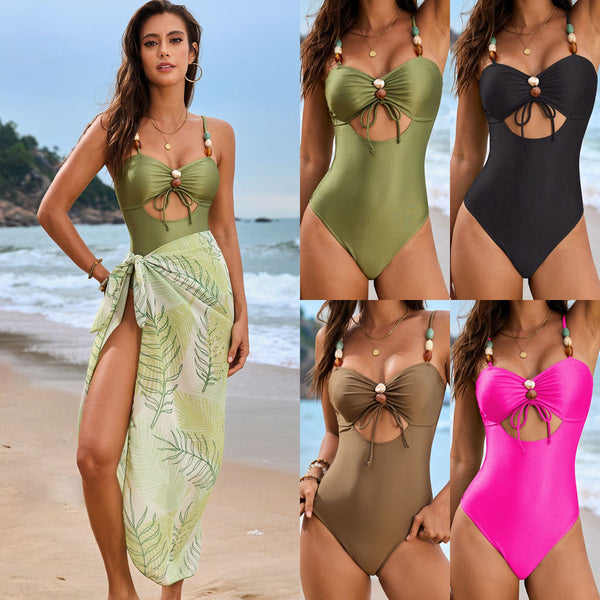 Olive green one-piece swimsuit with a front drawstring cutout and beaded straps, worn by a woman on a beach.
