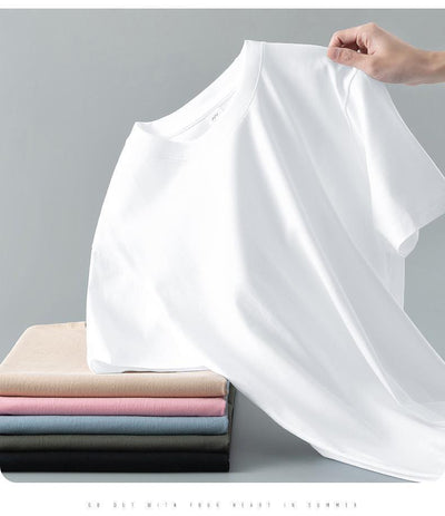 Light gray short-sleeve t-shirt with a round neck, held up to show its smooth fabric. A stack of folded t-shirts in various colors is visible in the background. - Image 28