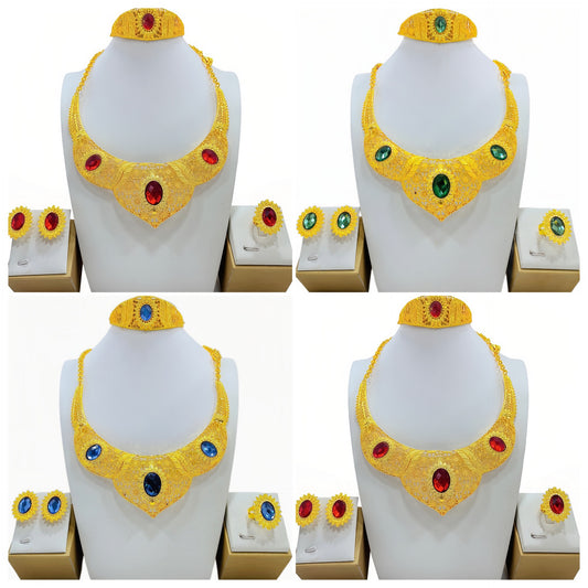 Golden jewelry set with a wide necklace, cuff bracelet, stud earrings, and ring, all featuring blue oval gemstones and intricate filigree patterns.