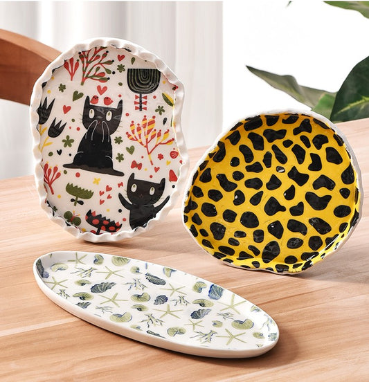 Ceramic plate with yellow cartoon leopard cat underglaze decals and a sheet of the same decals.