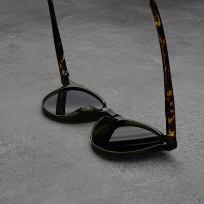 Fashionable round-frame sunglasses with transparent gray frames and dark gray lenses on a gray surface. - Image 14