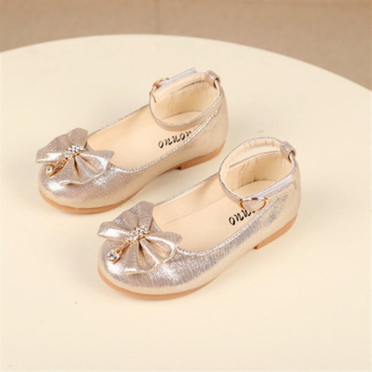 Shiny pink children's ballet flats with ankle straps, decorative bows, and rhinestone embellishments.