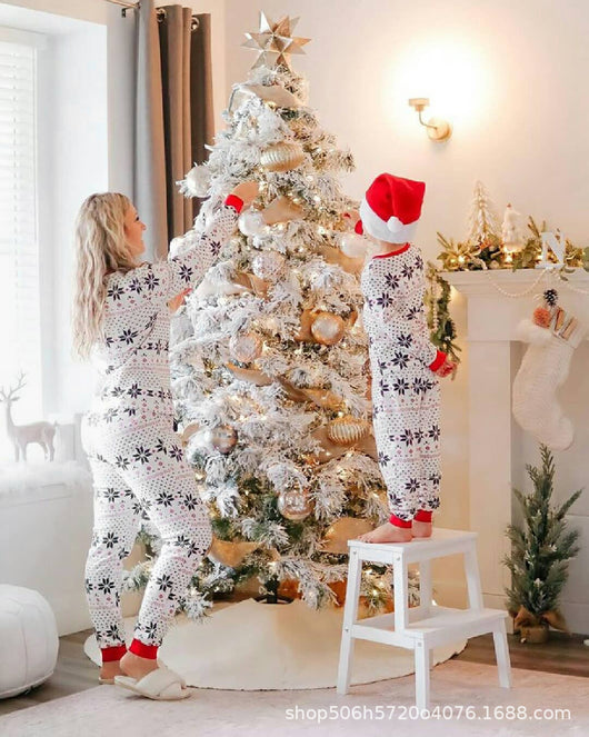 Family of six wearing matching white Christmas pajamas with black snowflake and red trim, posing by a decorated staircase. - Image 5