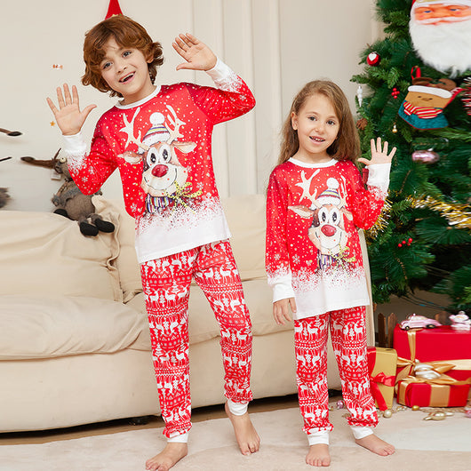 Family of four wearing matching red Christmas pajamas with reindeer and snowflake patterns, sitting on a sofa. - Image 7