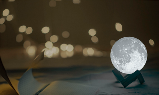 Moon-shaped humidifier and night light with a white deer stand, emitting mist, on a wooden table with books. - Image 12