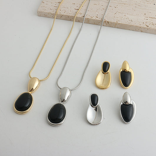 Pair of gold-toned irregular earrings with black onyx-like inserts, featuring a modern, abstract design. - Image 17