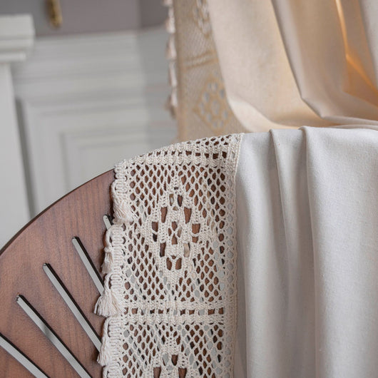 Close-up of a beige semi-transparent curtain with a delicate crochet lace trim and decorative tassels. - Image 14