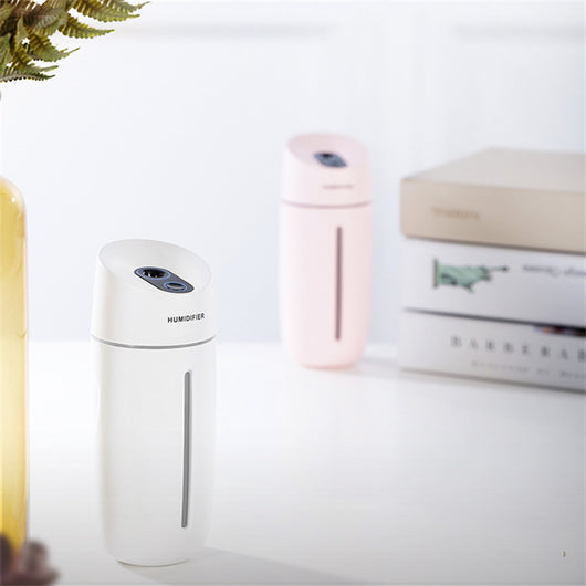 White desktop humidifier with blue LED light strip and control buttons, emitting mist on a wooden surface. - Image 11