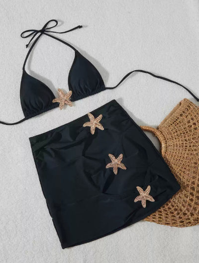 Black three-piece bikini set with triangle top, thong bottom, and skirt, all featuring gold starfish embellishments. - Image 5
