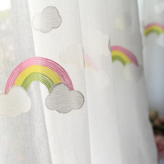 White sheer gauze curtain with colorful embroidered rainbows and grey clouds, suitable for a child's room.