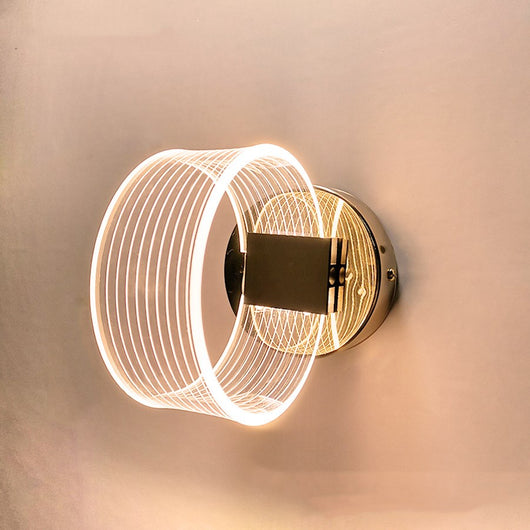 Modern simple LED wall lamp with a curved clear acrylic shade and a metallic base, emitting a warm light.