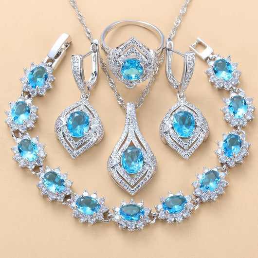 4-piece women's jewelry set with silver-tone necklace, ring, earrings, and bracelet, featuring red oval gemstones surrounded by clear accent stones. - Image 6