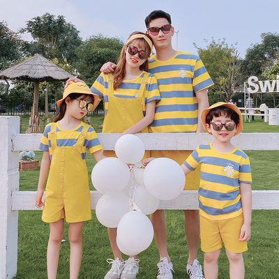 Family of four wearing matching yellow and blue striped t-shirts with daisy appliques. Mother and daughter wear yellow short overalls, father and son wear yello - Image 3
