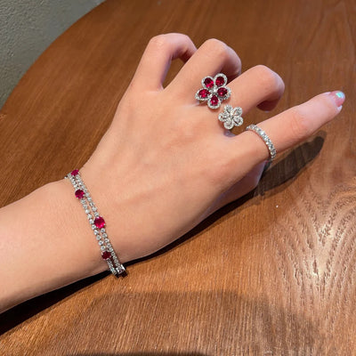Silver-tone ring with two flower designs, one with crimson gemstones and clear zircons, the other with clear zircons. - Image 3