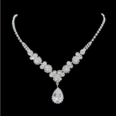 Sparkling silver-toned necklace and matching teardrop earrings set with clear stones, displayed on a black stand. - Image 7