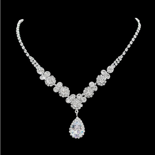 Sparkling silver-toned necklace and matching teardrop earrings set with clear stones, displayed on a black stand. - Image 7
