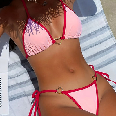 Pink and red halter-style triangle bikini with heart-shaped hardware and tie-up thong bottom, worn on a beach.
