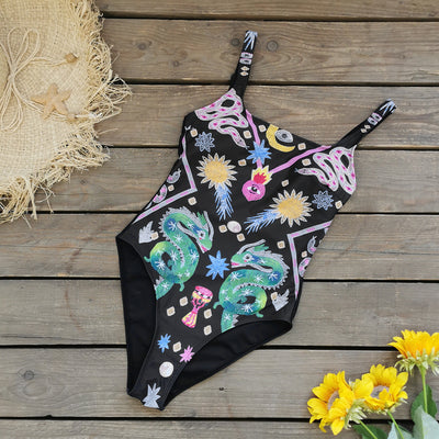 Black one-piece swimsuit for women featuring a vibrant multi-color print with dragons, suns, moons, and stars. - Image 2