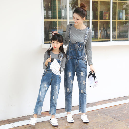 Mother and daughter wearing matching distressed denim overalls over black and white striped long-sleeve shirts. - Image 4