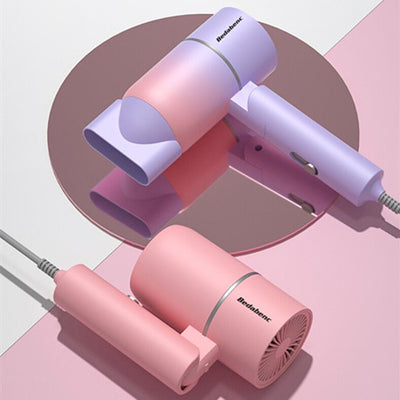 White portable folding hair dryer with rose gold accents and a nozzle attachment, shown with its base. - Image 10