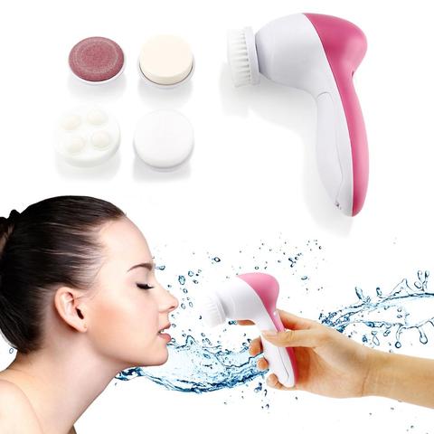 White electric facial cleanser with multiple brush and sponge attachments in an open translucent teal carrying case.