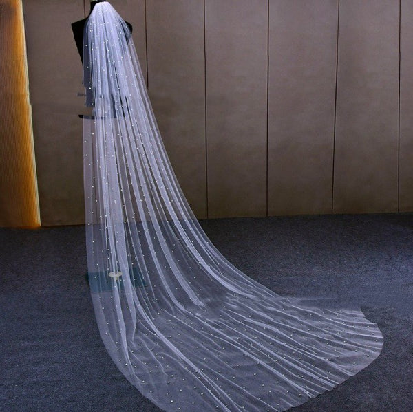Mid-length white bridal veil with scattered pearl embellishments, flowing elegantly on a mannequin.