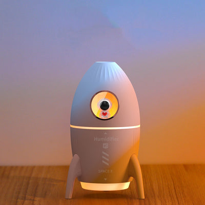 Pink rocket-shaped humidifier with an astronaut figurine in a circular window and a glowing yellow light band. - Image 5