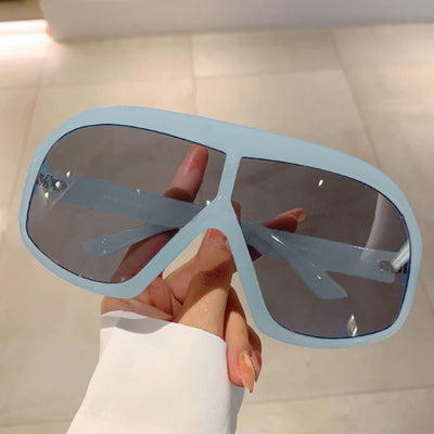 Oversized women's shield sunglasses with a tortoiseshell frame and brown-tinted lenses, held by a hand. - Image 7