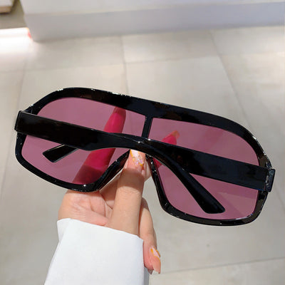 Oversized women's shield sunglasses with a tortoiseshell frame and brown-tinted lenses, held by a hand. - Image 15