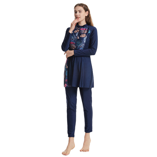 Woman in a navy blue quick-drying conservative swimwear set with a tropical leaf print tunic and matching swim cap. - Image 2