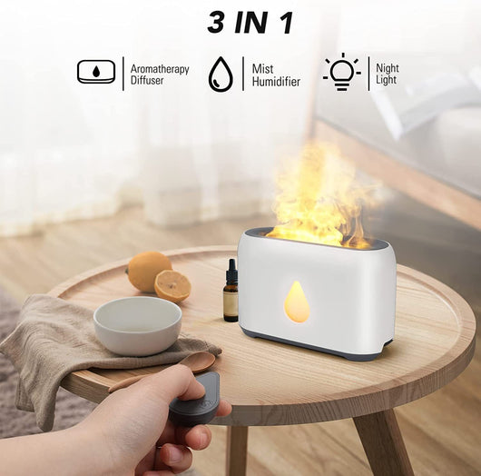 White aroma diffuser with a 3D flame effect and a gold water droplet icon, shown with a remote control.