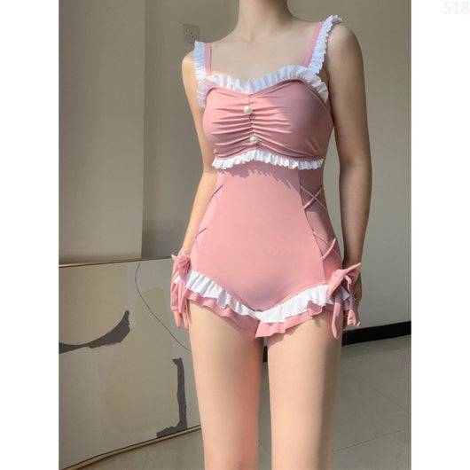 Pink one-piece swimming suit with white ruffles, ruched bust, pearl buttons, and shorts-style bottom with side ties. - Image 8