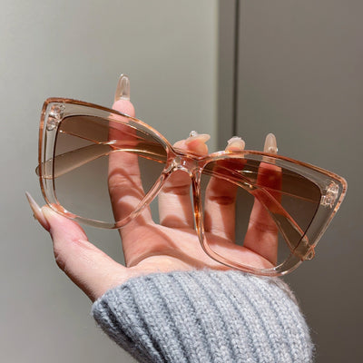 Clear large-frame square glasses held by a hand in a grey knitted sweater, showcasing the transparent plastic frame. - Image 10