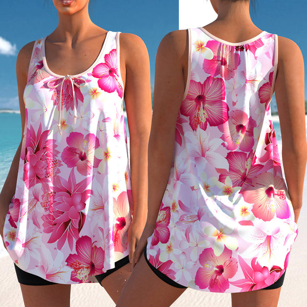 Woman wearing a pink and white floral print tankini top with black swim shorts on a sunny beach.