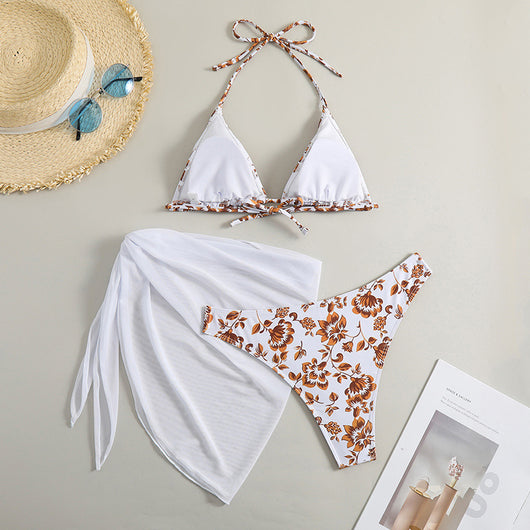 White and yellow floral print three-piece bikini set with a halter triangle top, high-cut bottom, and sheer white sarong. - Image 25