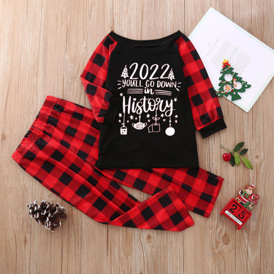 White long-sleeve pajama top with "wild one" graphic and red and black plaid pants.