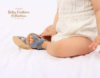 Black baby sandals with knotted cross straps and a matching black floral headband on a white background. - Image 34