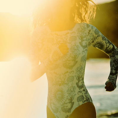 White one-piece swimsuit with a blue sun and intricate floral pattern, featuring a scoop neck and wide straps. - Image 3