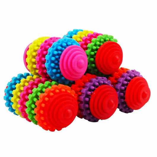 A hand holds a colorful rubber dog toy ball with seven interlocking gear-like rings in purple, orange, green, red, yellow, pink, and blue. - Image 3