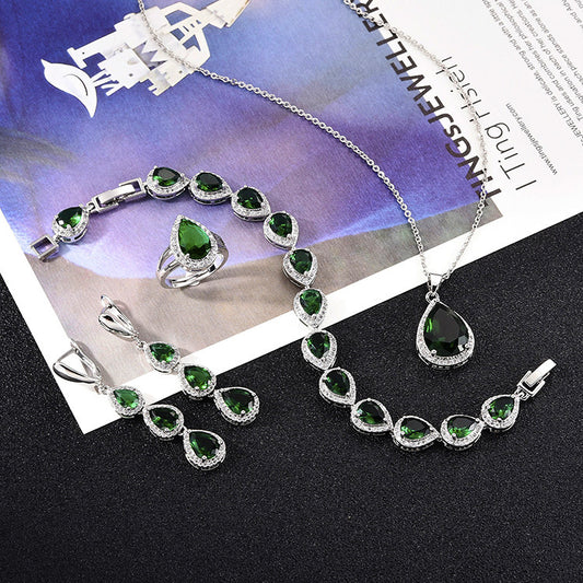 Green pear-shaped gemstone jewelry set with necklace, dangle earrings, ring, and bracelet, all with clear stone accents.