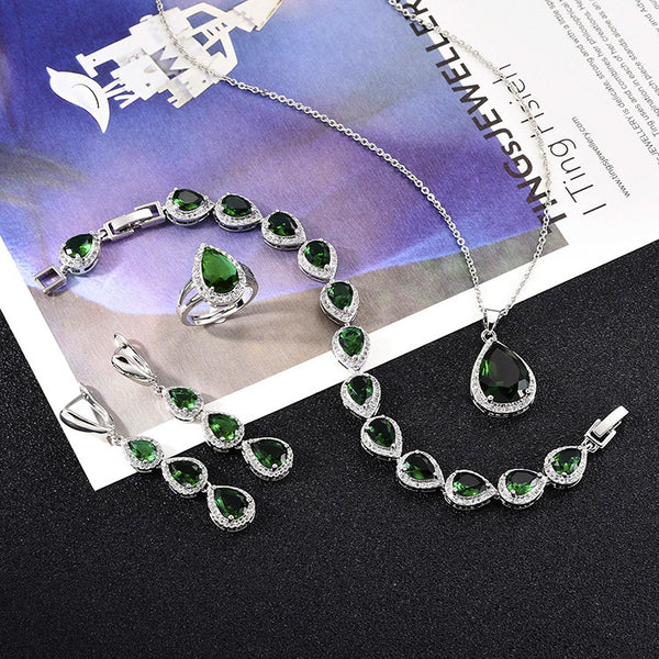 Green pear-shaped gemstone jewelry set with necklace, dangle earrings, ring, and bracelet, all with clear stone accents.