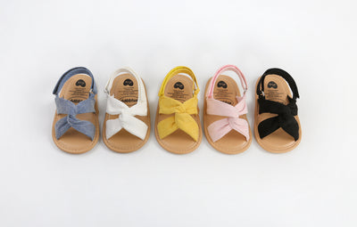 Black baby sandals with knotted cross straps and a matching black floral headband on a white background. - Image 20