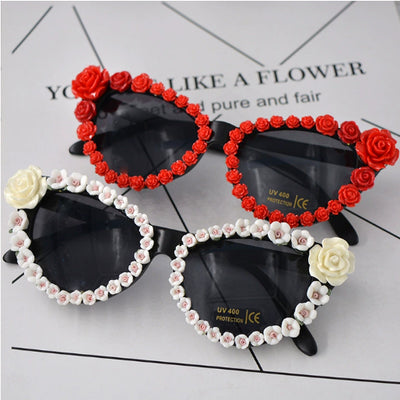 Black cat-eye sunglasses with dark lenses, adorned with small red rose embellishments along the frames. - Image 9