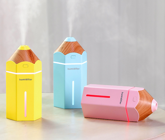 Light blue pencil-shaped mini humidifier with wood-grain top and glowing green light, next to a white teacup and pink gift box. - Image 2