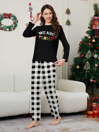 Family of four wearing matching black long-sleeve pajamas with "WE ARE FAMILY" text and black and white plaid bottoms. - Image 11