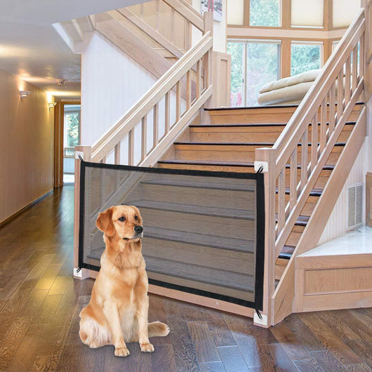 Black mesh pet gate installed at the bottom of a wooden staircase, with a golden retriever sitting in front. - Image 4