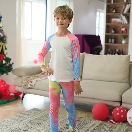 Family of four wearing matching pink, blue, and yellow tie-dye long-sleeved pajama sets in a living room. - Image 2