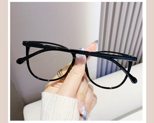 Black full-frame round anti-blue light glasses held by a hand with a gold ring and light blue gradient nails. - Image 23