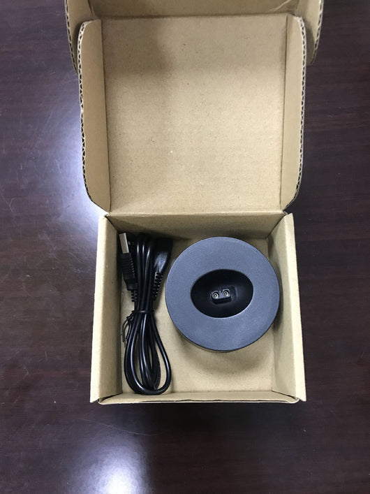 Black round charging base and coiled USB cable inside an open brown cardboard box on a dark wooden surface. - Image 7